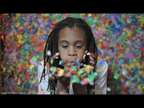 Black child holding confetti in hands and blowing out